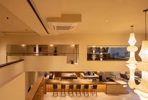 Warm and inviting restaurant interior with wooden floors, beige walls, and a bar area with stools, surrounded by dining tables and chairs