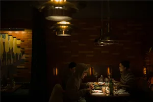 A group of people dining together in a warm and inviting Asian restaurant setting with a dining table, chairs, wine glasses, and various tableware