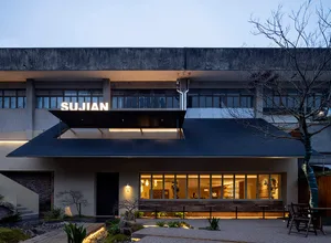 Modern building with a large roof overhang, featuring a mix of concrete, wood, and metal materials, with natural light entering through several windows