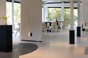 A modern restaurant dining area with a large table and chairs, well-lit and welcoming