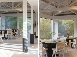 A well-lit dining area with chairs and tables, featuring a large window that lets in natural light