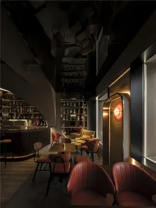 Cozy restaurant with wooden floors and walls, comfortable seating areas, and multiple bottles on tables