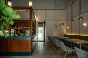 Inviting coffee shop interior with a counter, chairs, couches, and cups, perfect for enjoying a cup of coffee or conversation