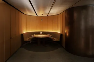 A modern dining space with a round table, chairs, and benches, dimly lit for a cozy atmosphere