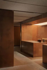 A warm and inviting kitchen with a brown wooden theme, featuring a wooden countertop and a brown-tinted wall, with two bottles and a bowl placed on the counter