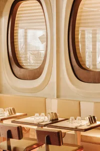 Elegant dining space with wooden elements, tables, chairs, and wine glasses, set in a warm and inviting atmosphere
