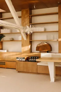 Cozy open living area with wooden floors and walls, featuring a couch, dining table, and kitchenette, with warm tones and inviting atmosphere