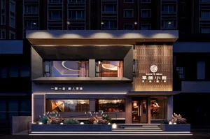 A modern Asian restaurant at night with a gray concrete exterior, earth-toned interior, and warm lighting