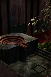 A modern bathroom with a large stone sink basin featuring a marble finish and flowing water, set against a neutral background