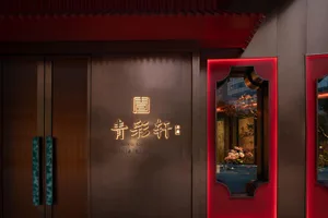 A modern Asian restaurant with red walls, large windows, and potted plants, featuring decorative elements and a welcoming atmosphere