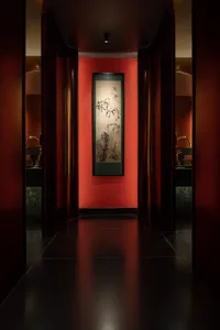 Bathroom with red walls, green painting, two sinks, and a large picture above the sinks