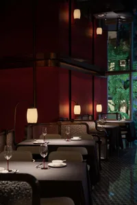 Elegant restaurant interior with red walls, black tables, and wine glasses, creating a sophisticated atmosphere