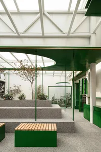 A bright and welcoming indoor space with a large glass wall, potted plants, and benches for seating