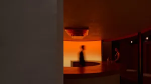 A warm and inviting bar scene with a circular counter, a bottle, and two people enjoying their time