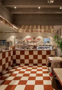 A restaurant interior with a checkered tile floor, dining tables, chairs, and counters displaying food items
