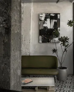 A green couch in a living area with two potted plants and a book, creating a comfortable and inviting atmosphere