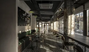 A modern cafe with a large dining table, multiple chairs, and benches, featuring a warm atmosphere with green and brown tones and natural light