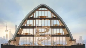 Modern building with a large glass structure resembling a giant letter B, featuring multiple windows and a sleek, sophisticated appearance