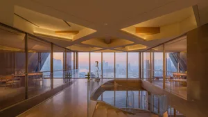 A bright and inviting hotel lobby with a glass staircase, natural light, and a modern design