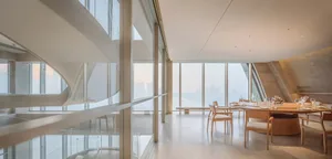 Open living space with a dining table, chairs, and a couch near a large window with natural light