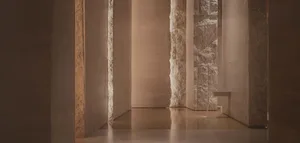Grand hallway with stone walls, marble floors, and two large pillars, featuring a classical style and warm lighting