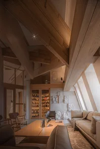 Open living area with wooden floors and walls, featuring a combined kitchen, dining room, and living room with furniture and decorative items