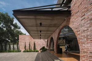 A classic building with a brick facade, overhang, and potted plants around the entrance, creating a welcoming atmosphere