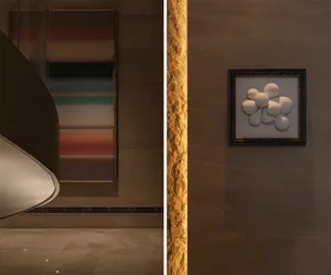 Elegant interior space with artwork, a clock, and a stone wall, featuring a mix of framed pictures and a painting