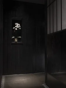 Dark wooden hallway with a vase of flowers on a window sill, surrounded by potted plants and a calm atmosphere