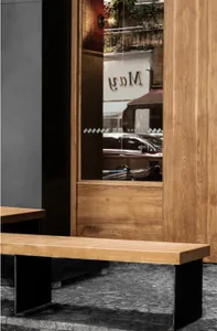 A cozy cafe with a wooden doorway leading to a dining area, featuring two benches and a view of a car outside through the window