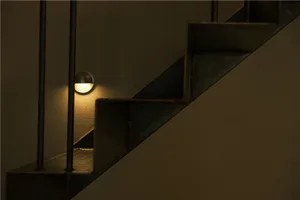 A dimly lit stairwell with metal railing, two lights on either side of the stairs, and a residential building interior