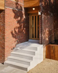 A classic brick building with a wooden doorway, stairs, and a small balcony, exuding a sense of history and charm
