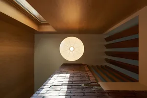 A staircase made of wood leads to a brick wall in a space with a blend of traditional and modern design elements
