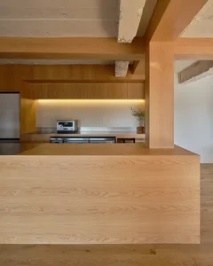 A warm and inviting kitchen with wooden floors and cabinets, featuring two sinks, a microwave, and multiple potted plants