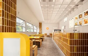 Bright and inviting dining space with multiple tables and chairs, natural light, and warm yellow walls