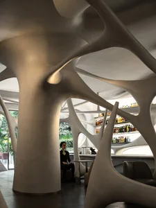 A modern bar area with a curved wall, bottles, and seating for patrons