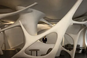 A spacious modern interior design concept featuring curved walls, white surfaces, and a dining table with chairs, with a person standing nearby