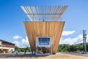 An open-air restaurant with a wooden structure surrounded by trees, featuring chairs and tables in a serene natural setting