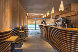 Warm and inviting restaurant interior with wooden walls and floors, featuring benches, chairs, and a dining table