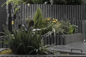 A serene indoor garden area with various plants in pots and a small waterfall, creating a lively atmosphere for relaxation and nature appreciation
