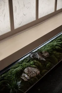 A serene indoor space with a large window and a rock garden below, featuring various sized rocks and natural elements