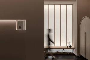 A person walks through a calm and serene interior space with two potted plants and a vase on a surface near the center