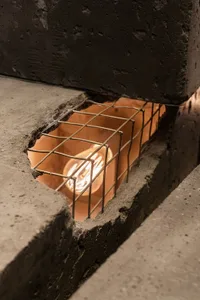 Industrial space with a brick wall and metal grate, lit by two side lights, giving a rugged and utilitarian feel