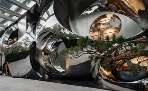 A modern interior space with a black and white color scheme, featuring a large tree in the center surrounded by various rooms and industrial elements