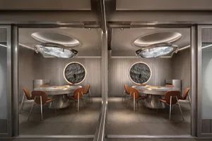 A well-lit restaurant dining area with multiple round tables and chairs, gray and white walls, and a comfortable atmosphere