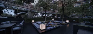 A relaxed outdoor patio scene with a fire pit surrounded by chairs and dining tables, perfect for social gatherings or warm evenings