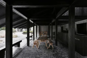 A cozy dining area with a wooden table and chairs in a black and white room with dim lighting