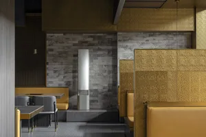 Empty restaurant interior with yellow walls, two dining tables, and a bench, creating a cozy atmosphere for dining and socializing