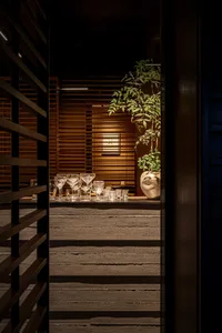 A cozy indoor space with a wooden bar area, wine glasses, and vases, creating a warm and inviting atmosphere for social gatherings