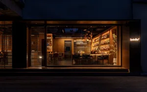 溫馨酒吧餐廳配木質家具、椅子與餐桌，柔和燈光照亮，飾以酒瓶與玻璃杯